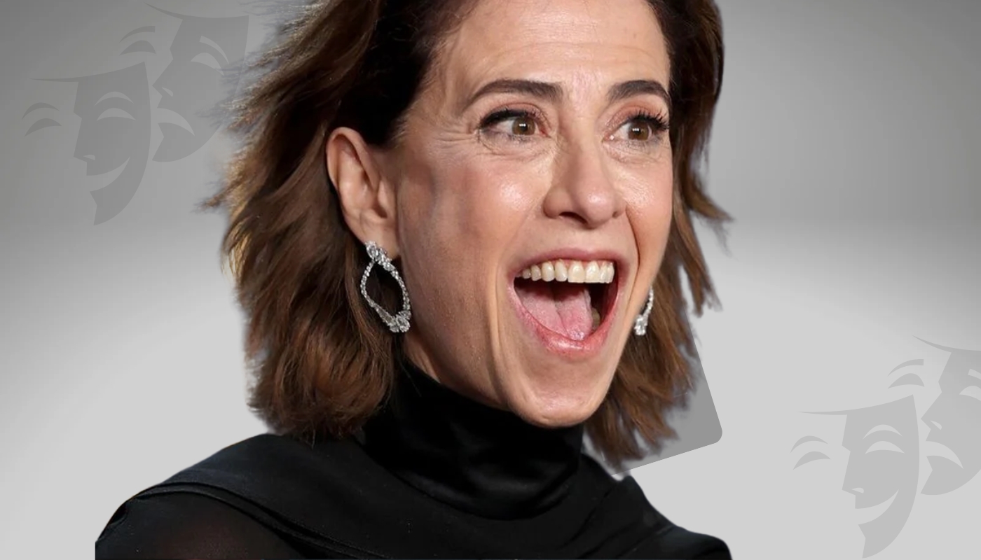 Close-up of a smiling actress wearing elegant earrings and a black outfit, expressing joy