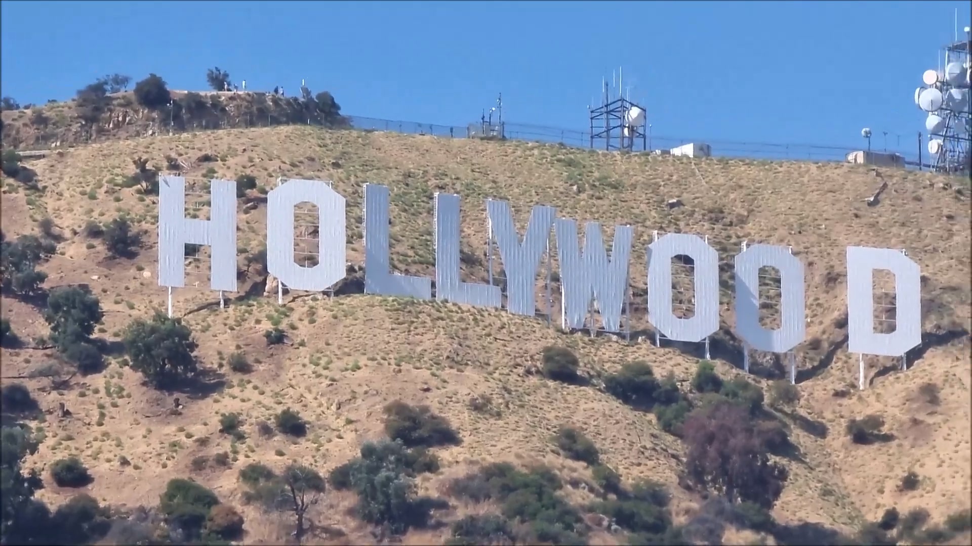 The Hollywood Sign on a sunny day, set on a hillside with a clear blue sky in the background