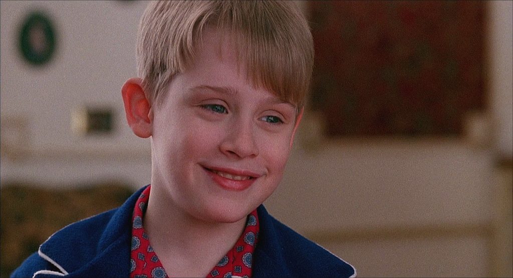 Young Macaulay Culkin, the most iconic child stars, smiling in a scene from Home Alone, portraying Kevin McCallister