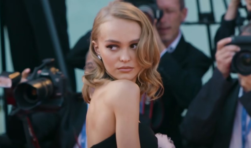 Lily-Rose Depp captured on a red carpet event, surrounded by photographers