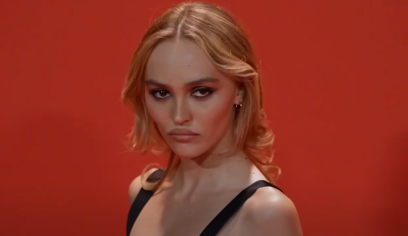 Lily-Rose Depp poses in front of the red background
