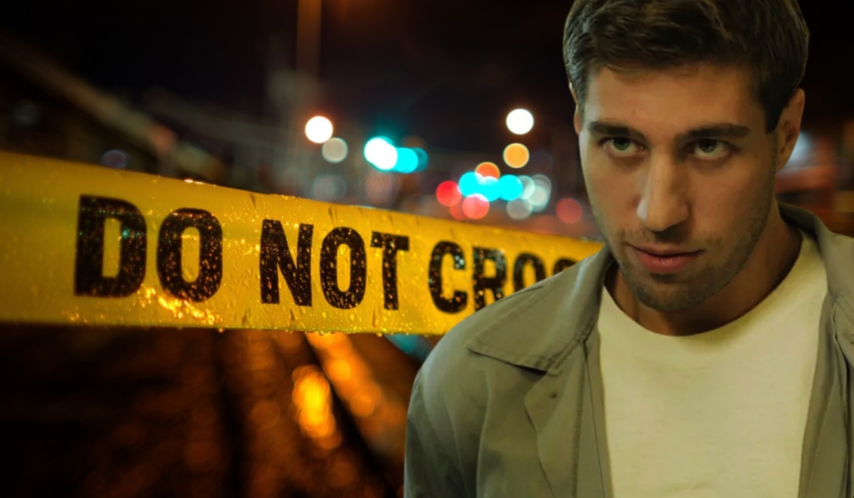 Man standing in front of crime scene tape with 'Do Not Cross' written on it, at night